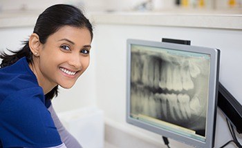 Dental assistant looking at x rays of teeth on computer