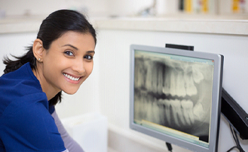 A dentist looking at a dental X ray on a computer screen