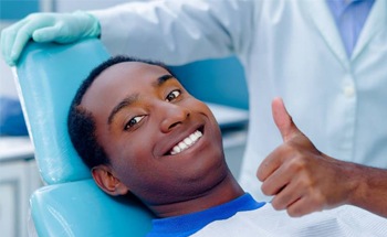 Man smiling and giving thumbs up in dental chair