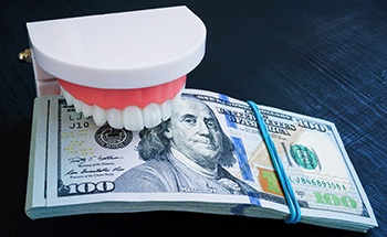 a stack of money with a model of teeth biting down on it